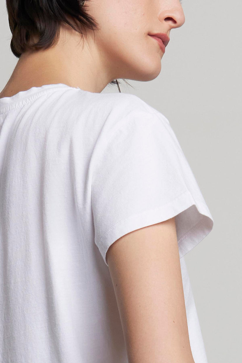 The person is wearing a relaxed-fit TOPANGA TEE by Velvet by Jenny Graham, a white short-sleeve shirt made from organic cotton. They are turned partially away from the camera, showing their right side and back.