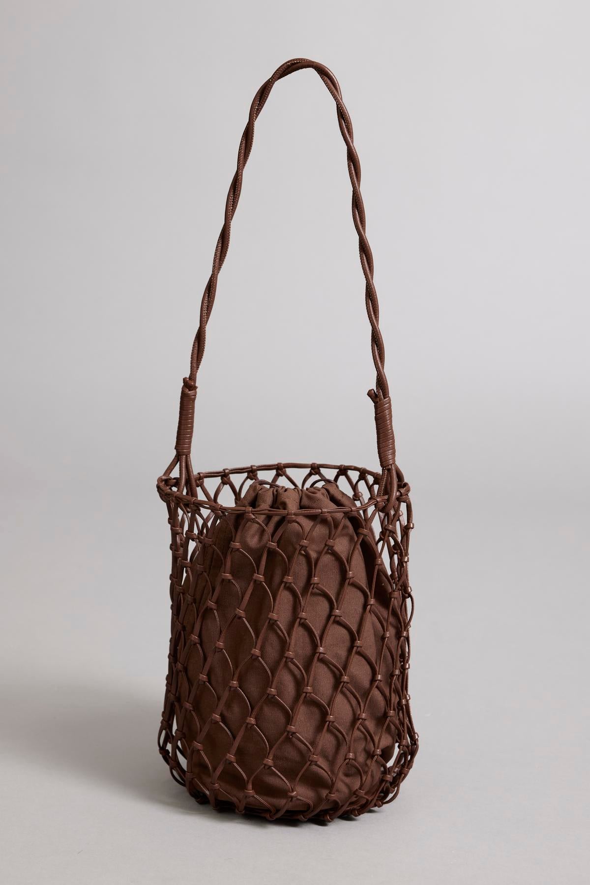   Brown vegan leather Velvet by Graham & Spencer mesh tote bag with a long braided handle on a neutral background. 