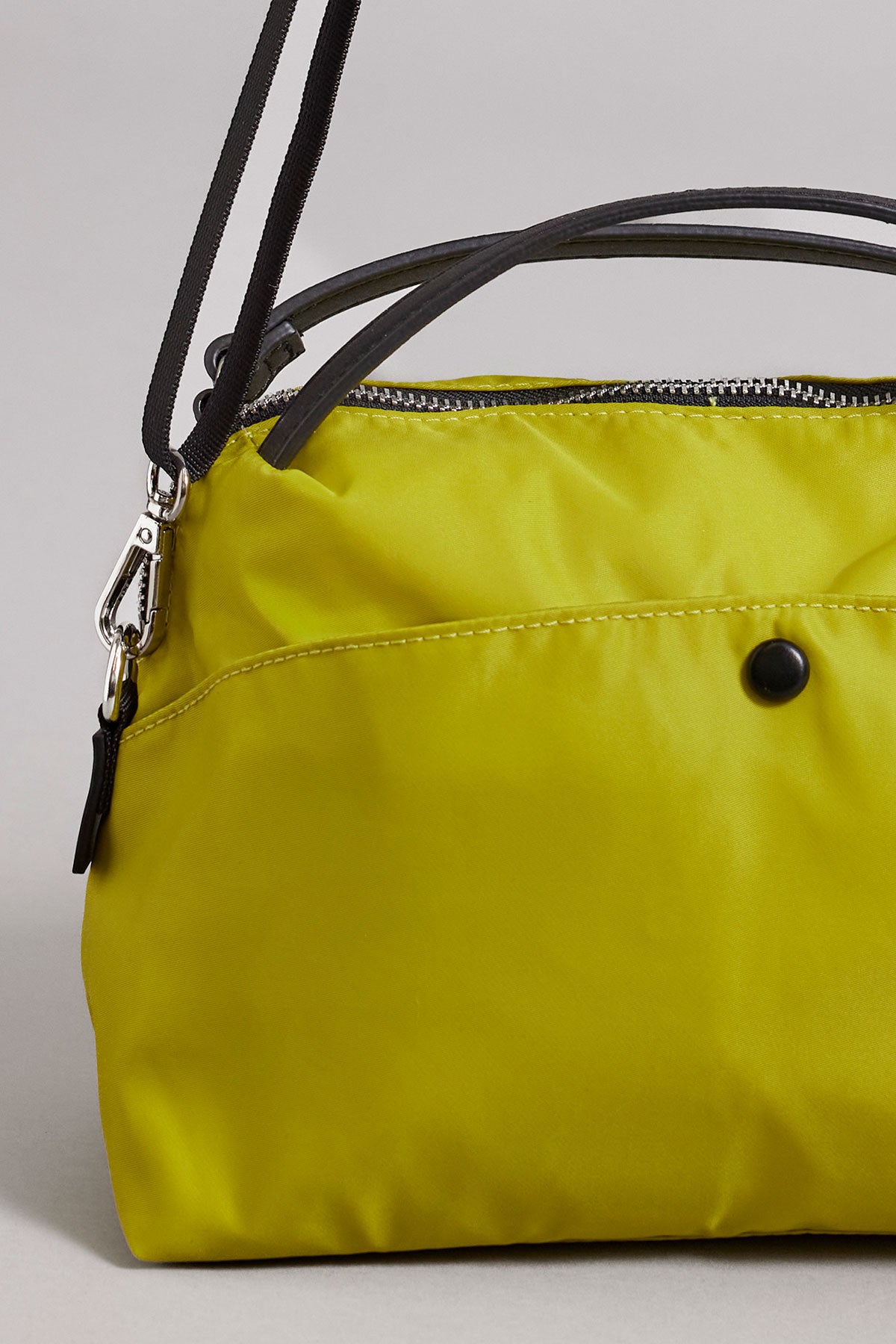   A yellow Velvet by Graham & Spencer NYLON CROSSBODY BAG with black leather handles and shoulder straps, featuring a secure zipper closure and a black button detail on the front. 