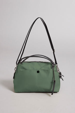 The NYLON CROSSBODY BAG by Velvet by Graham & Spencer is a green nylon handbag featuring black straps and silver hardware, shown against a plain light background. Ideal for everyday use, it offers a zip closure and a front pocket accented with a small black button.