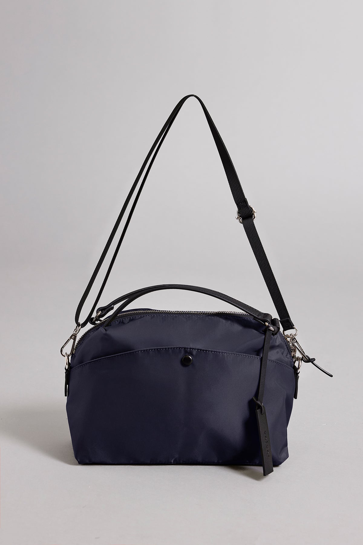 A small, dark blue Velvet by Graham & Spencer NYLON CROSSBODY BAG with black adjustable straps and a zippered pocket on the front against a plain background. This durable Velvet by Graham & Spencer NYLON CROSSBODY BAG also features a removable strap for versatile carrying options.-37355934515393