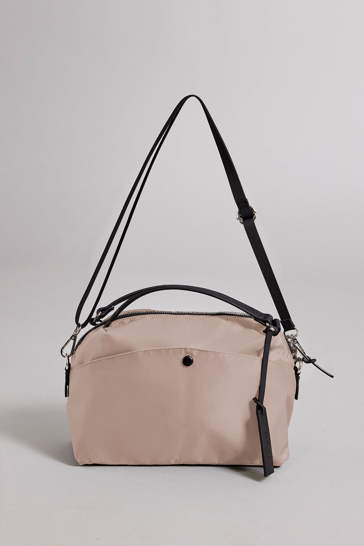 The Velvet by Graham & Spencer NYLON CROSSBODY BAG is a durable beige bag featuring black adjustable straps and zipper closure, ideal for everyday use. It's showcased against a plain gray background.-38896012492993