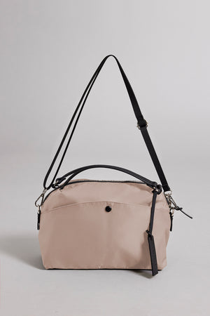 The Velvet by Graham & Spencer NYLON CROSSBODY BAG is a durable beige bag featuring black adjustable straps and zipper closure, ideal for everyday use. It's showcased against a plain gray background.