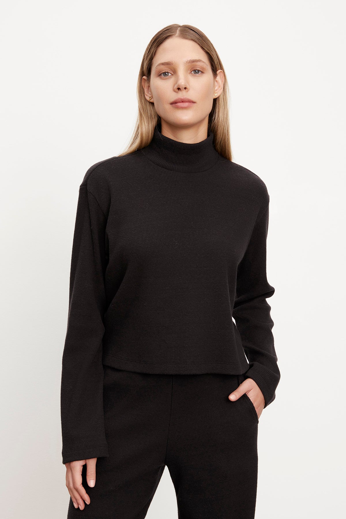 A woman wearing the Velvet by Graham & Spencer ALEC BRUSHED RIB TURTLENECK TOP and pants.-35701823439041