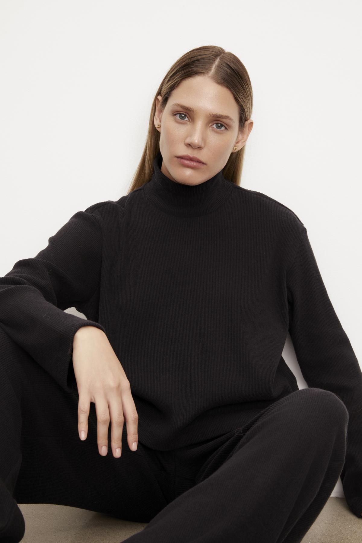 A model wearing a black Velvet by Graham & Spencer ALEC BRUSHED RIB MOCK NECK TOP and sweatpants.-35701823570113