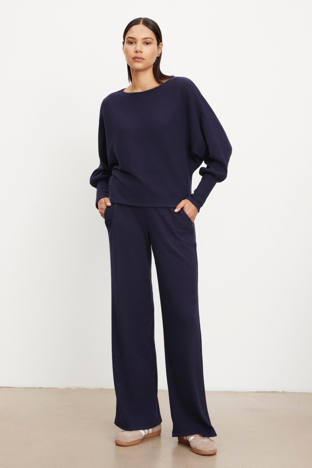 The model is wearing a Velvet by Graham & Spencer navy sweater and wide leg pants.-35702094692545