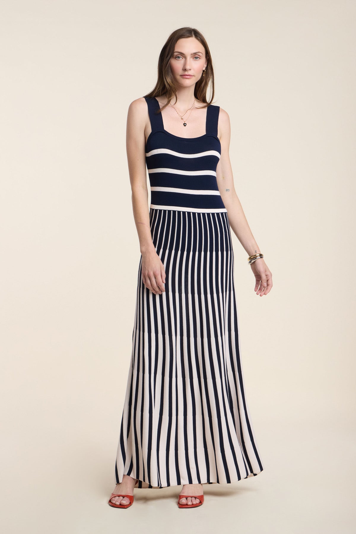 A woman models the AVELINE DRESS by Velvet by Graham & Spencer, featuring a sleeveless striped knit design with a fitted bodice and flared skirt, standing against a plain background.