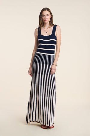 A woman models the AVELINE DRESS by Velvet by Graham & Spencer, a sleeveless maxi with a fitted bodice and navy and white stripes, standing against a plain light background.