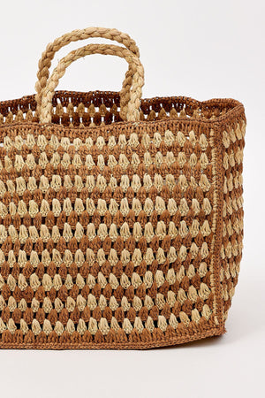 The MELODY BAG by Velvet by Graham & Spencer is a rectangular woven straw bag with two braided handles and a checkered pattern, shown against a plain white background.