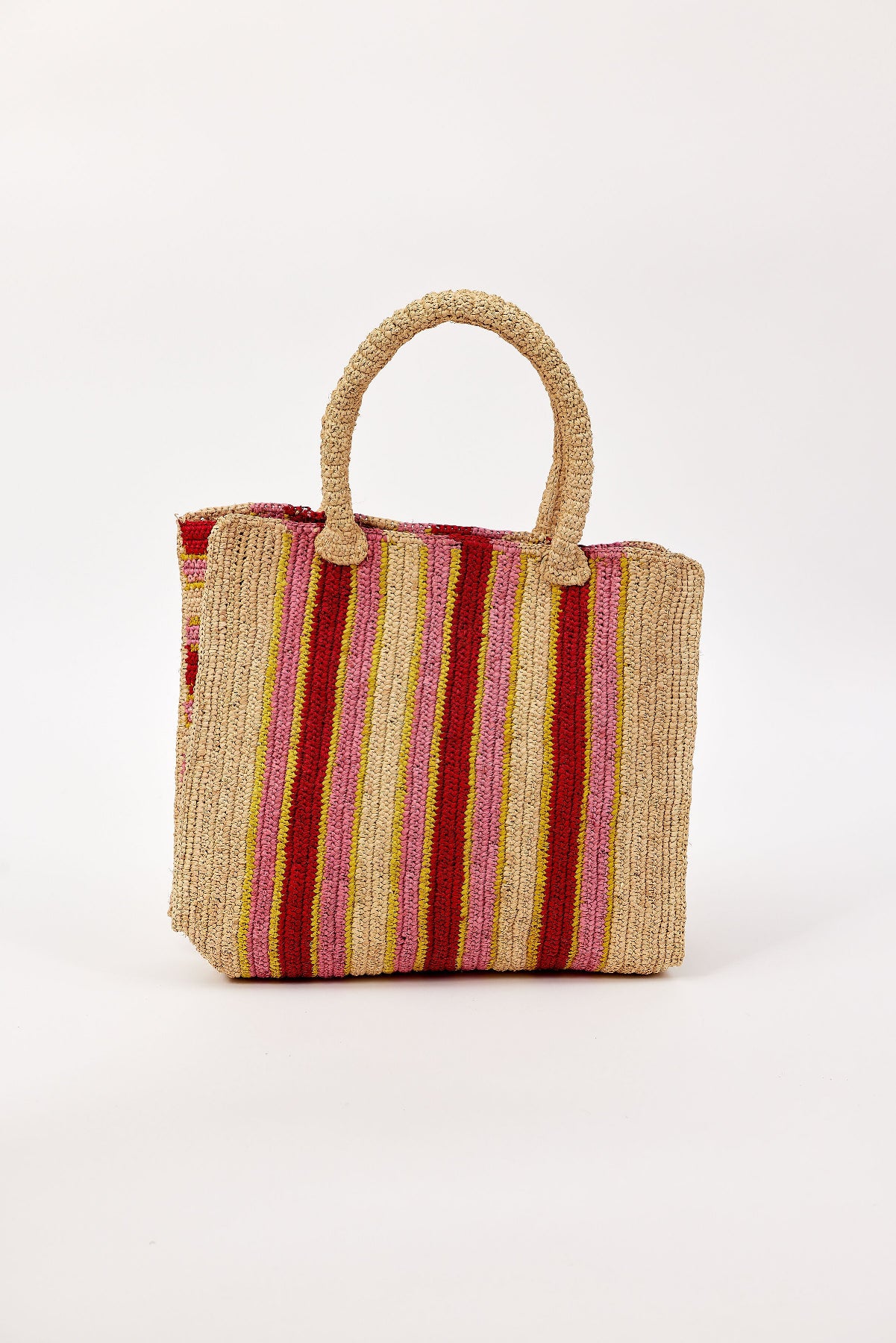 The ARLINGTON TOTE by Velvet by Graham & Spencer is a handcrafted raffia handbag with two handles, showcasing vertical beige, red, pink, and yellow stripes on a white background.