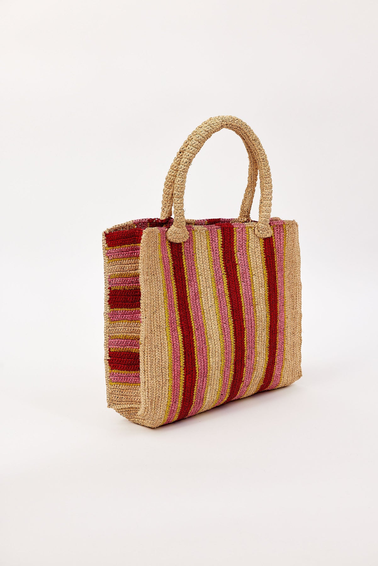 The ARLINGTON TOTE by Velvet by Graham & Spencer is a handcrafted raffia bag with dual handles and vertical stripes in red, pink, yellow, and beige—perfect for beach days—shown on a plain white background.-41393581064385
