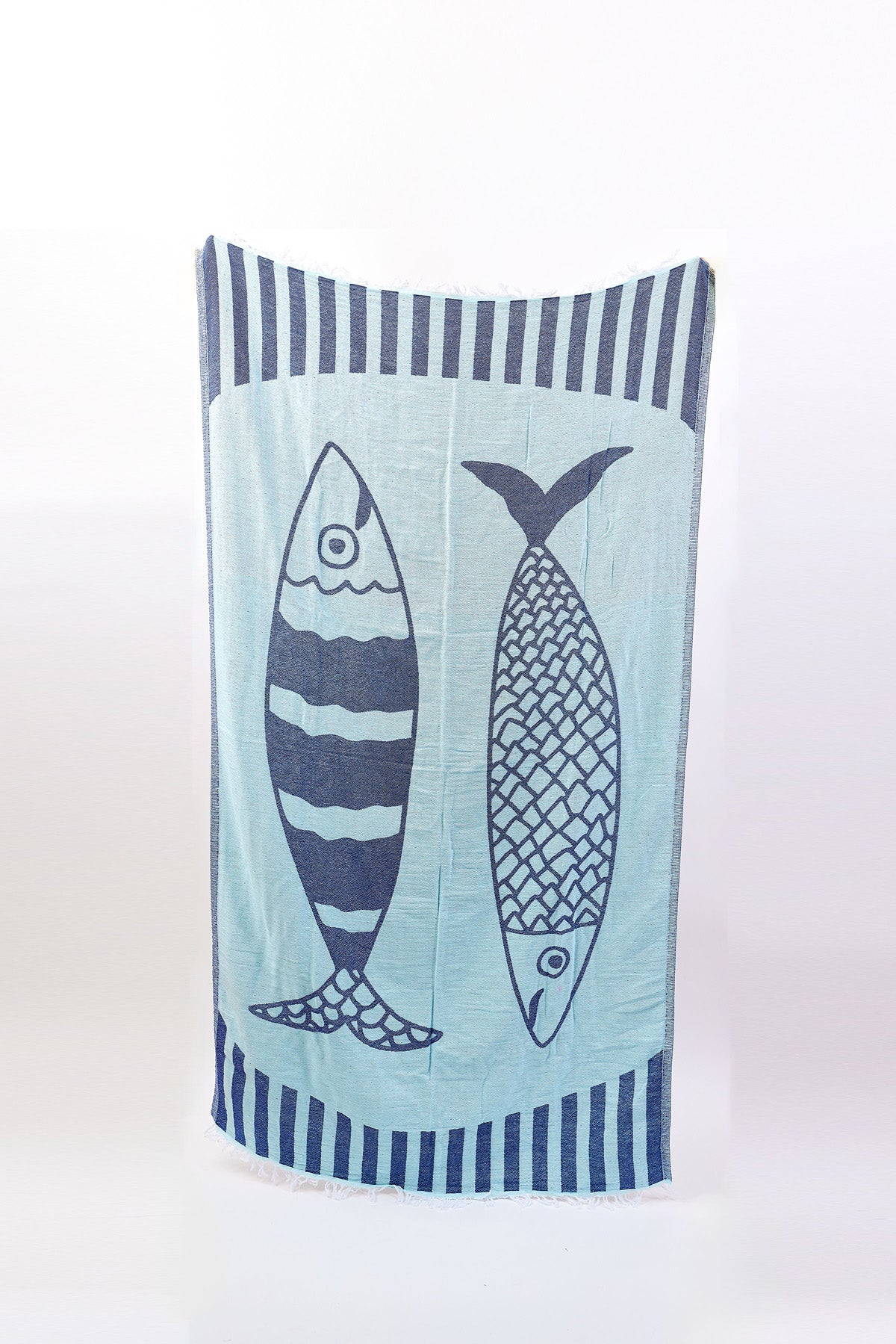 NOVELTY TURKISH TOWEL by Velvet by Graham & Spencer: a light blue cotton throw with two dark blue stylized fish and edge stripes—ideal as a beach blanket for sunny days.