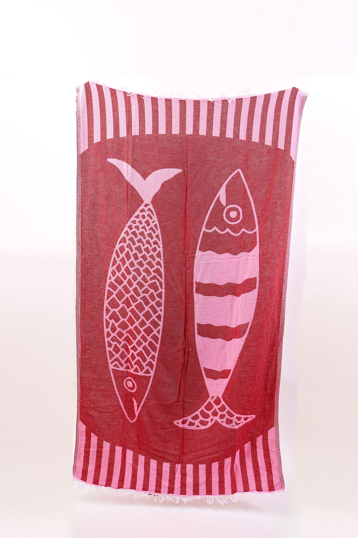 The NOVELTY TURKISH TOWEL by Velvet by Graham & Spencer is a rectangular red and pink cotton throw with two stylized fish designs in the center and striped borders.-41332175110337