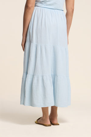 A person is shown from the back wearing the DANIELLE SKIRT by Velvet by Graham & Spencer—an ankle-length, cotton gauze tiered skirt with an elastic waist—paired with flat sandals.