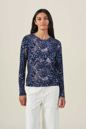 Velvet by Graham & Spencer LILIAN PRINTED TEE, a long-sleeved feather jersey crew neck t-shirt in a dark blue and lavender feather-like print, worn with cream trousers.