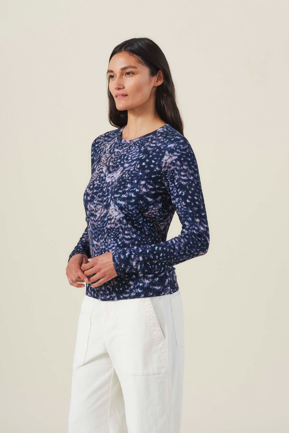 A woman wears a navy blue LILIAN PRINTED TEE with a textured, repeating abstract print and white pants.