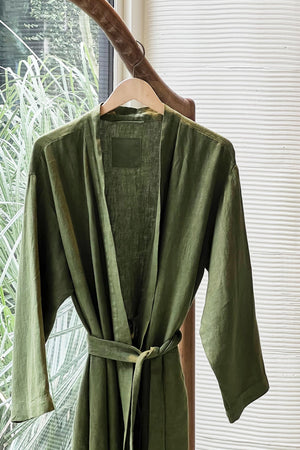 Jenny Graham Linen Robe in basil green on hanger near window