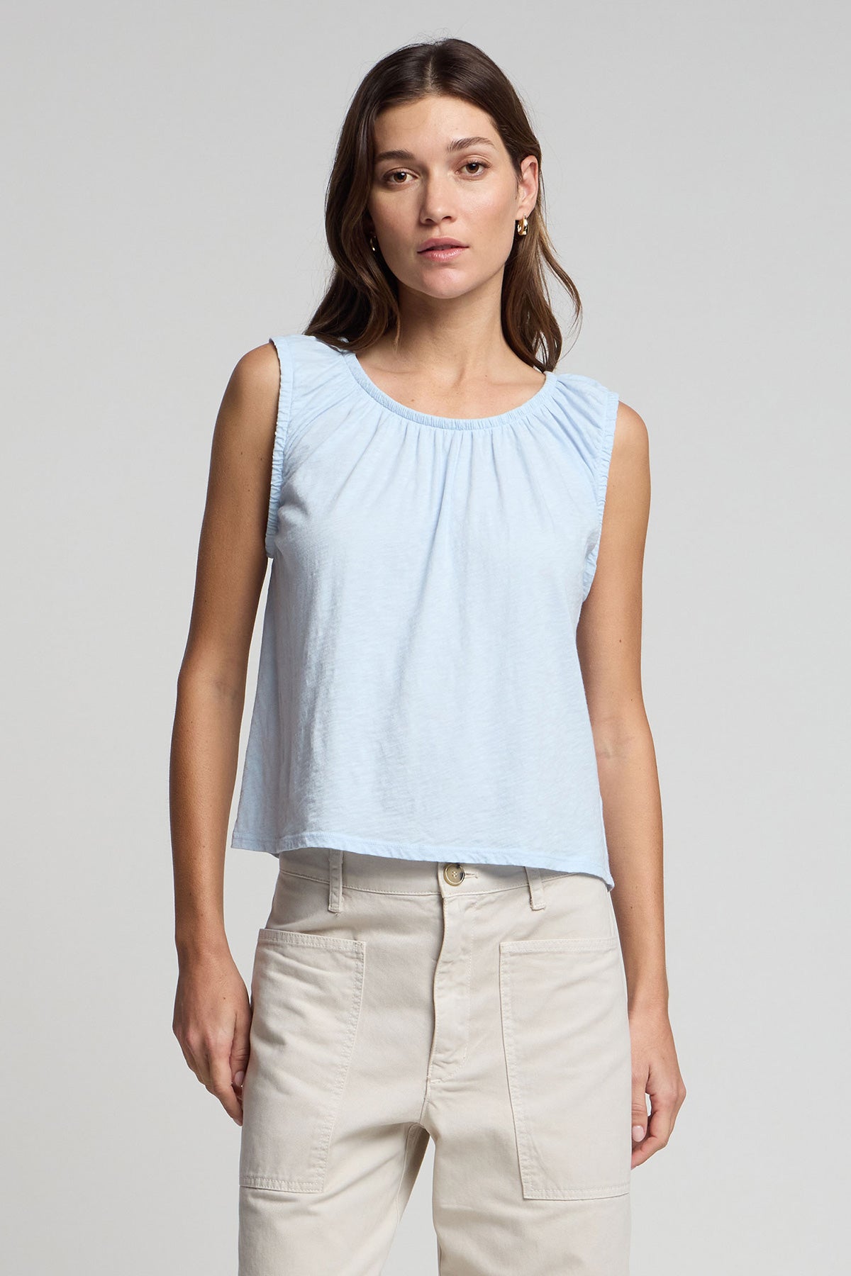 A woman faces the camera wearing the JUNA TANK TOP by Velvet by Graham & Spencer, styled with high-waisted beige pants against a plain light gray background.-41569247822017