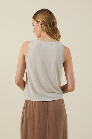 A woman with light brown hair faces away, wearing the KYLIE TANK TOP by Velvet by Graham & Spencer and a brown skirt, set against a plain light background.