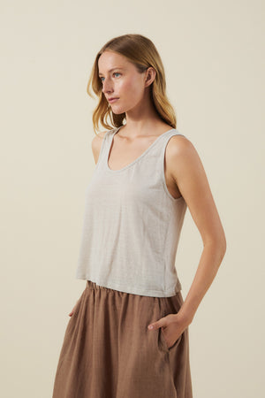 A woman in a light gray KYLIE TANK TOP by Velvet by Graham & Spencer and a brown skirt stands with her left hand in her pocket against a neutral background.