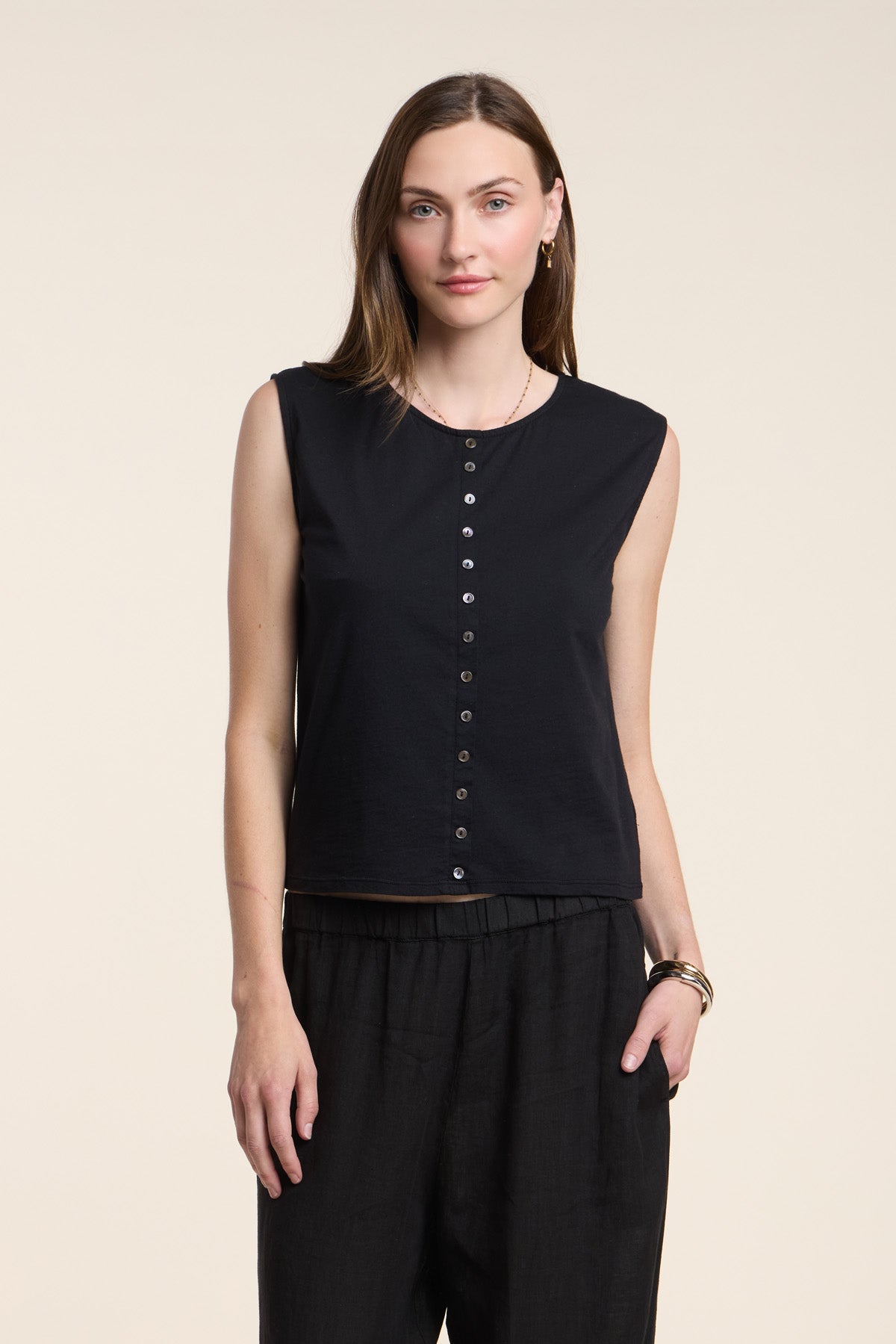 A woman wears the LACY TOP by Velvet by Graham & Spencer—a sleeveless black button-up—paired with black pants, standing against a plain light background.-41371953987777