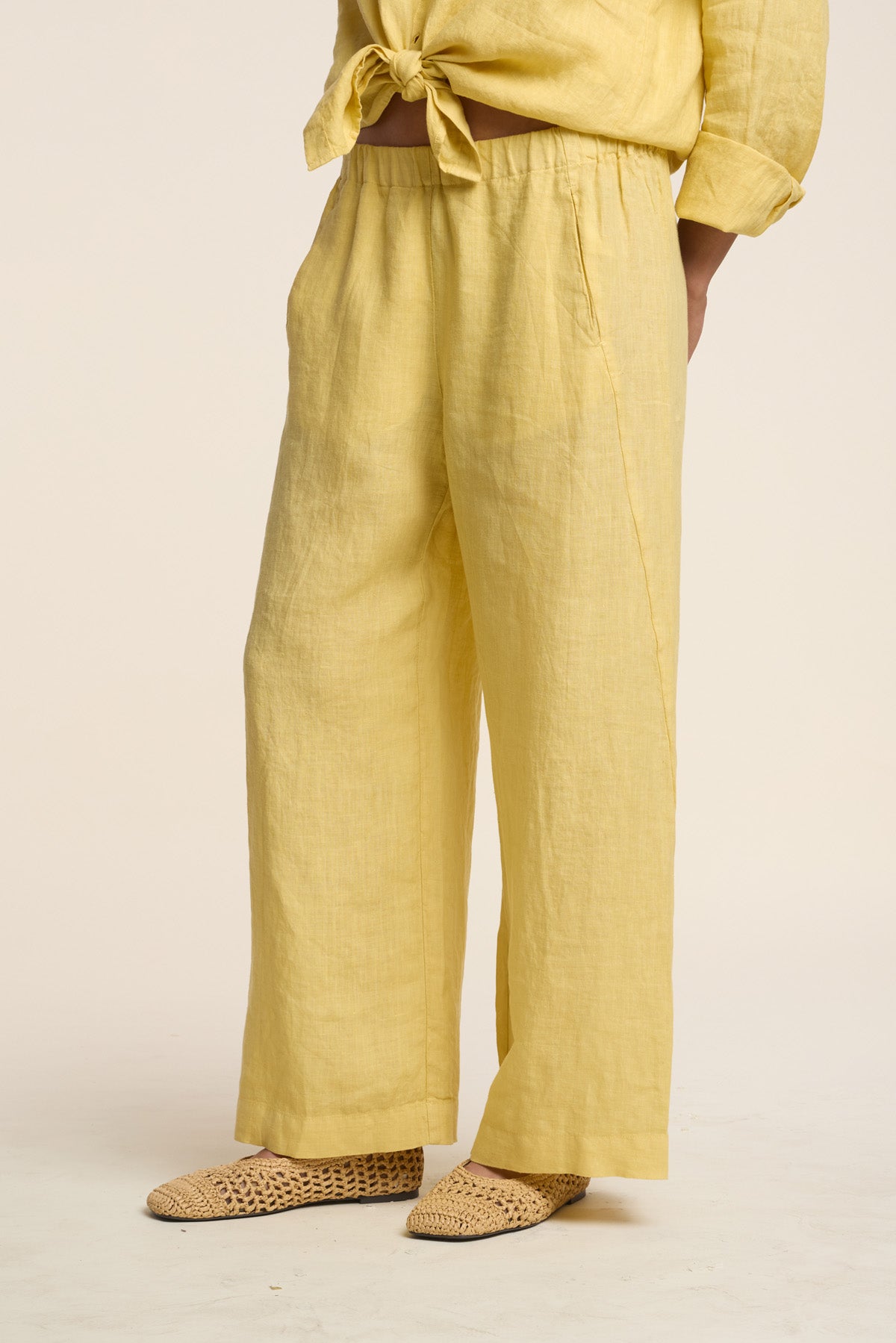 Wearing the LOLA LINEN PANT by Velvet by Graham & Spencer with a matching yellow top and woven beige shoes, this person stands against a neutral background.-41527071637697
