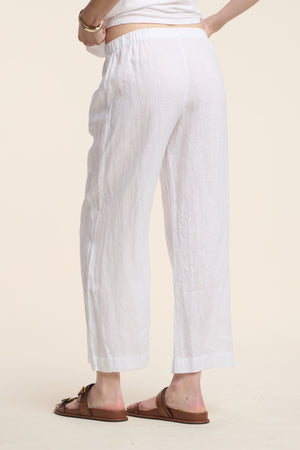 A person wearing the Velvet by Graham & Spencer LOLA LINEN PANT and brown sandals stands against a plain light background, shown from the back waist down.