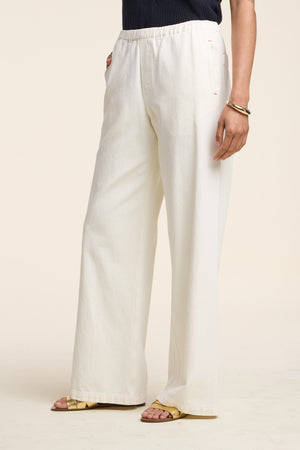 Wearing the LOUISE DENIM PANT by Velvet by Graham & Spencer—loose-fitting, high-waisted off-white denim with a relaxed silhouette—paired with a dark top, yellow sandals, and gold bangles against a plain background.