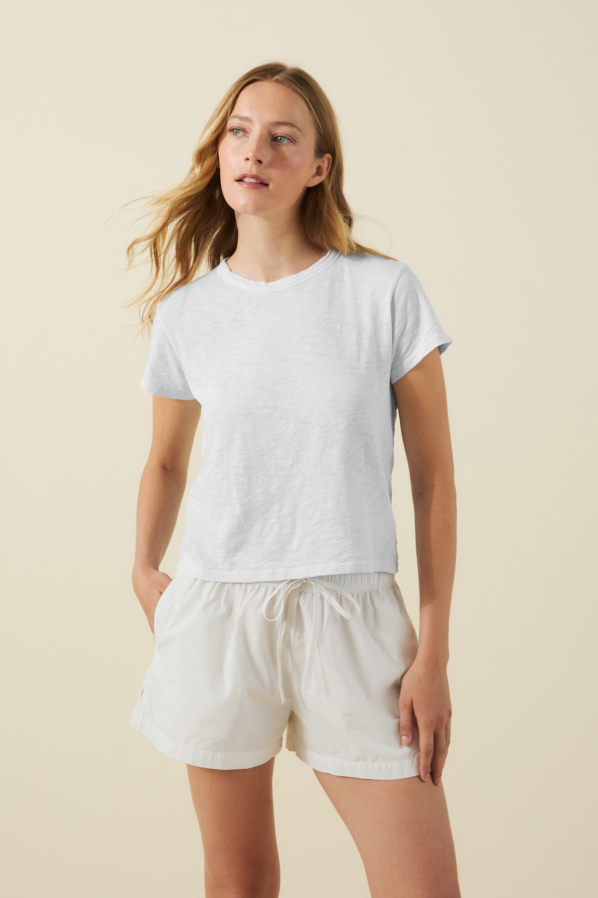 A woman wears the Velvet by Graham & Spencer MARIKA TEE in a boxy fit, paired with light-colored drawstring shorts, standing against a neutral background.