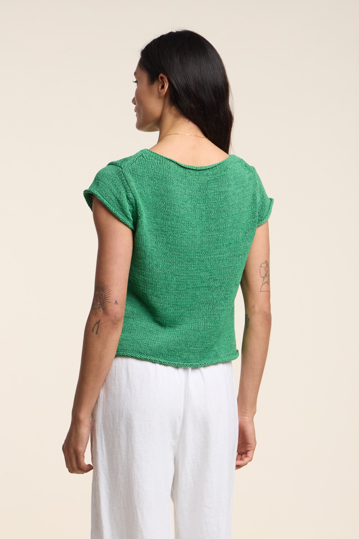 A person with long dark hair, shown from the back against a plain background, wears a green MILOU SWEATER by Velvet by Graham & Spencer and white pants.-41527100408001
