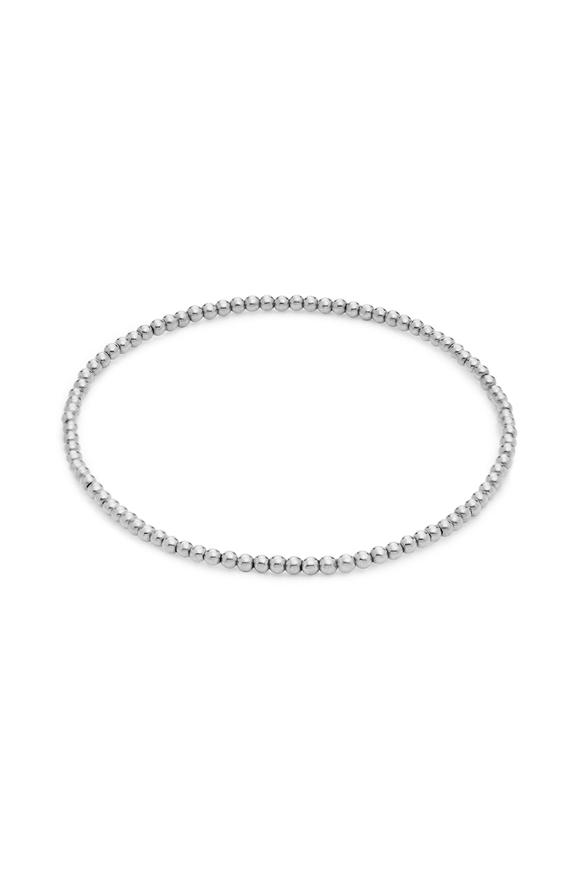 The MINI MOON BRACELET BY PHYLLIS AND ROSIE from Phyllis+Rosie is a simple, thin sterling silver beaded bracelet arranged in a circular shape with small, uniform spherical beads. This handcrafted piece of jewelry, inspired by vintage street culture, adds a touch of New York City flair against the plain white background.