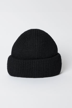 The MAJOR BEANIE by Velvet by Graham & Spencer is a black knit beanie hat featuring a classic cuffed design set against a white background, ideal for winter weather and perfect as a unisex accessory.