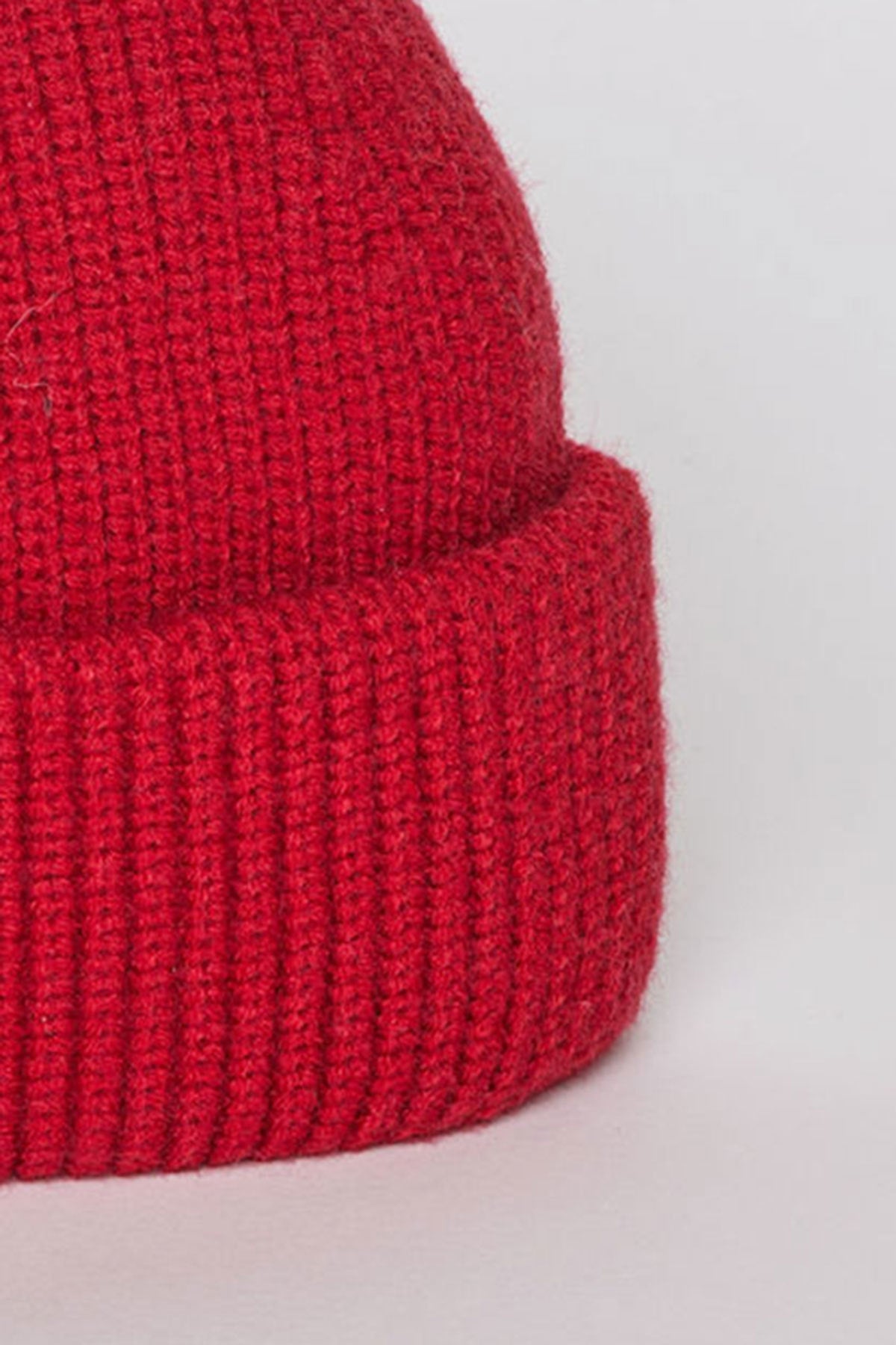   Close-up of a MAJOR BEANIE in red with a classic cuffed design by Velvet by Graham & Spencer against a plain background. 