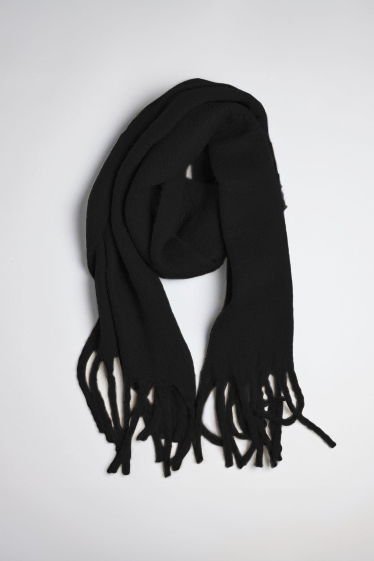   A CHIC SOLID SCARF from Velvet by Graham & Spencer featuring fringed ends is neatly laid out on a light gray surface. 