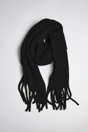 A CHIC SOLID SCARF from Velvet by Graham & Spencer featuring fringed ends is neatly laid out on a light gray surface.