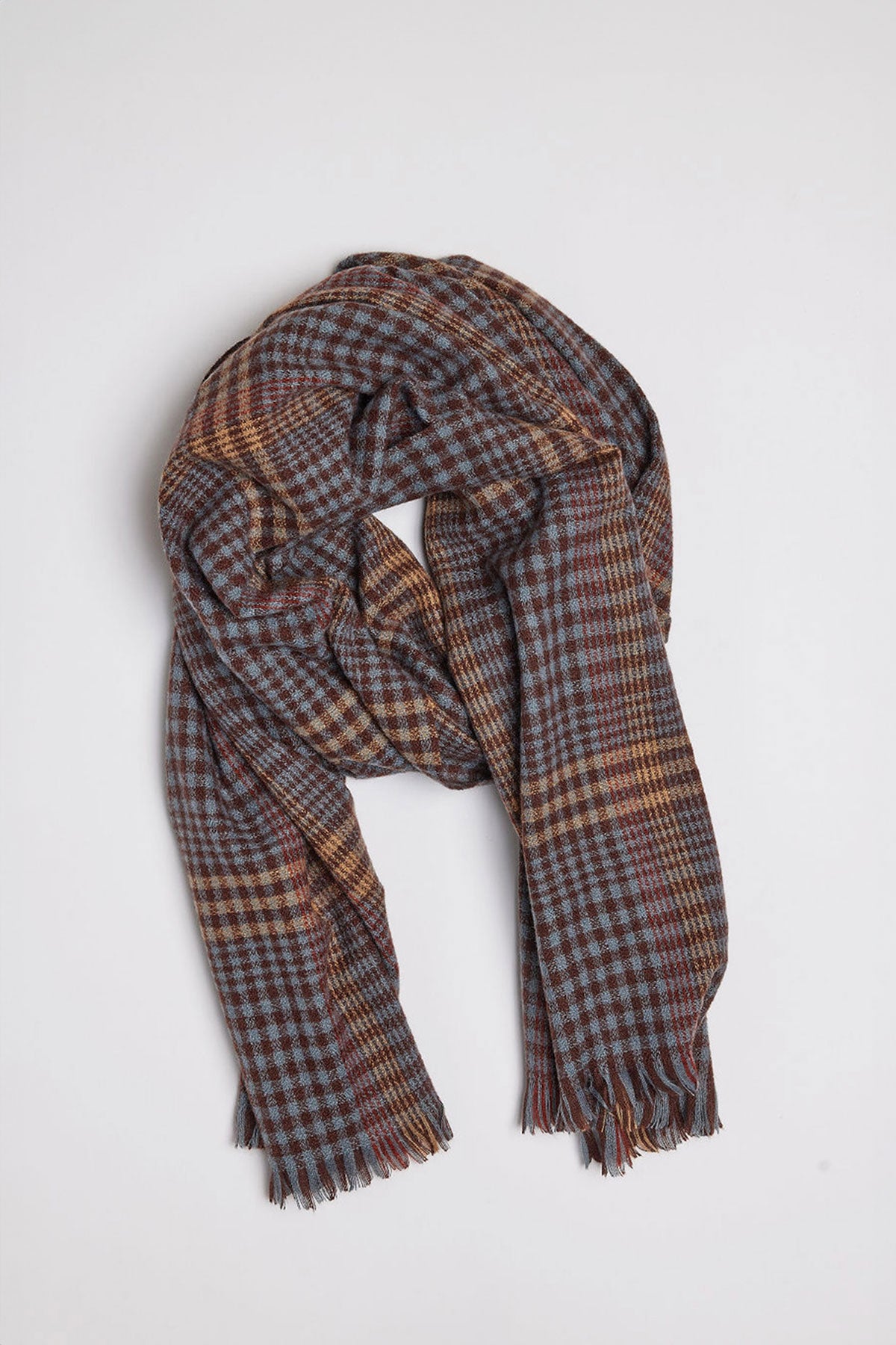   The STOWE SCARF by Velvet by Graham & Spencer, featuring a checked pattern with shades of blue, brown, and yellow, is loosely folded on a white background. 