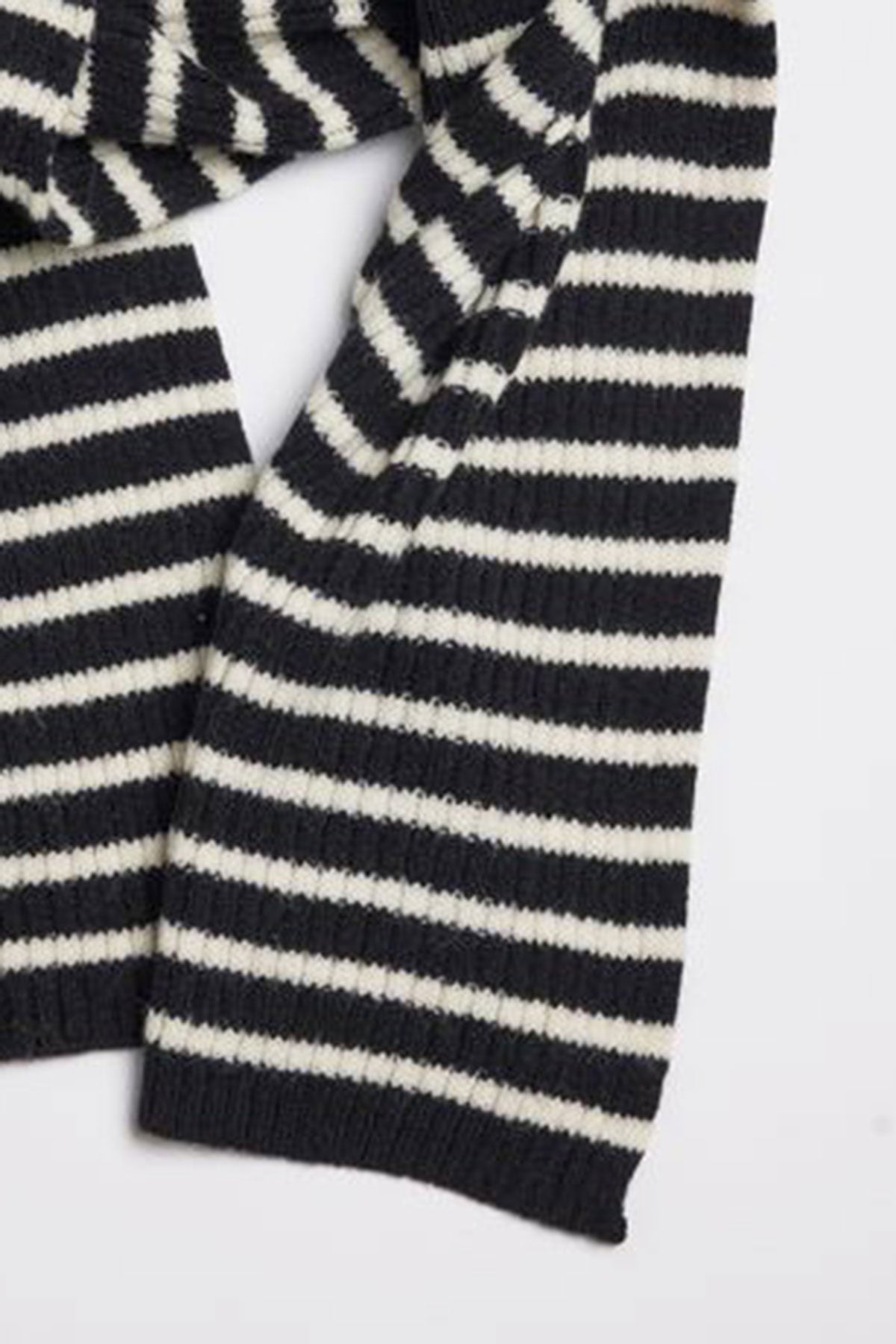   A close-up view of the BOLTON STRIPE SCARF by Velvet by Graham & Spencer, featuring black and white striped, ribbed fabric, displayed laid flat. 