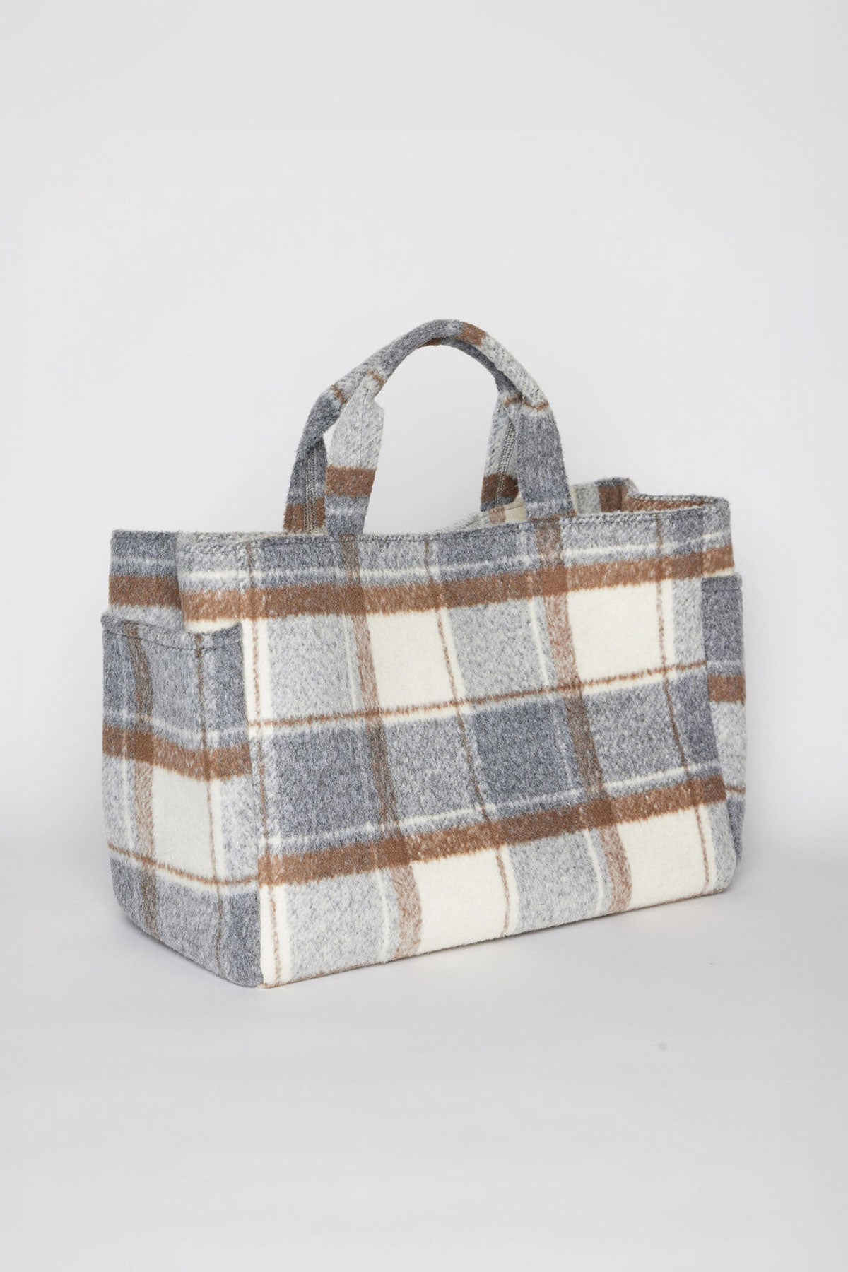   The PLAID TOTE by Velvet by Graham & Spencer is a rectangular woolen bag featuring a gray, brown, and white plaid pattern, complete with two short handles. 