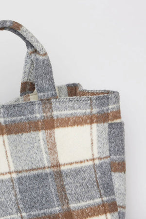 Close-up of the PLAID TOTE by Velvet by Graham & Spencer, showcasing its plaid pattern in shades of gray, brown, and beige. The handle is positioned on the top left of the image.