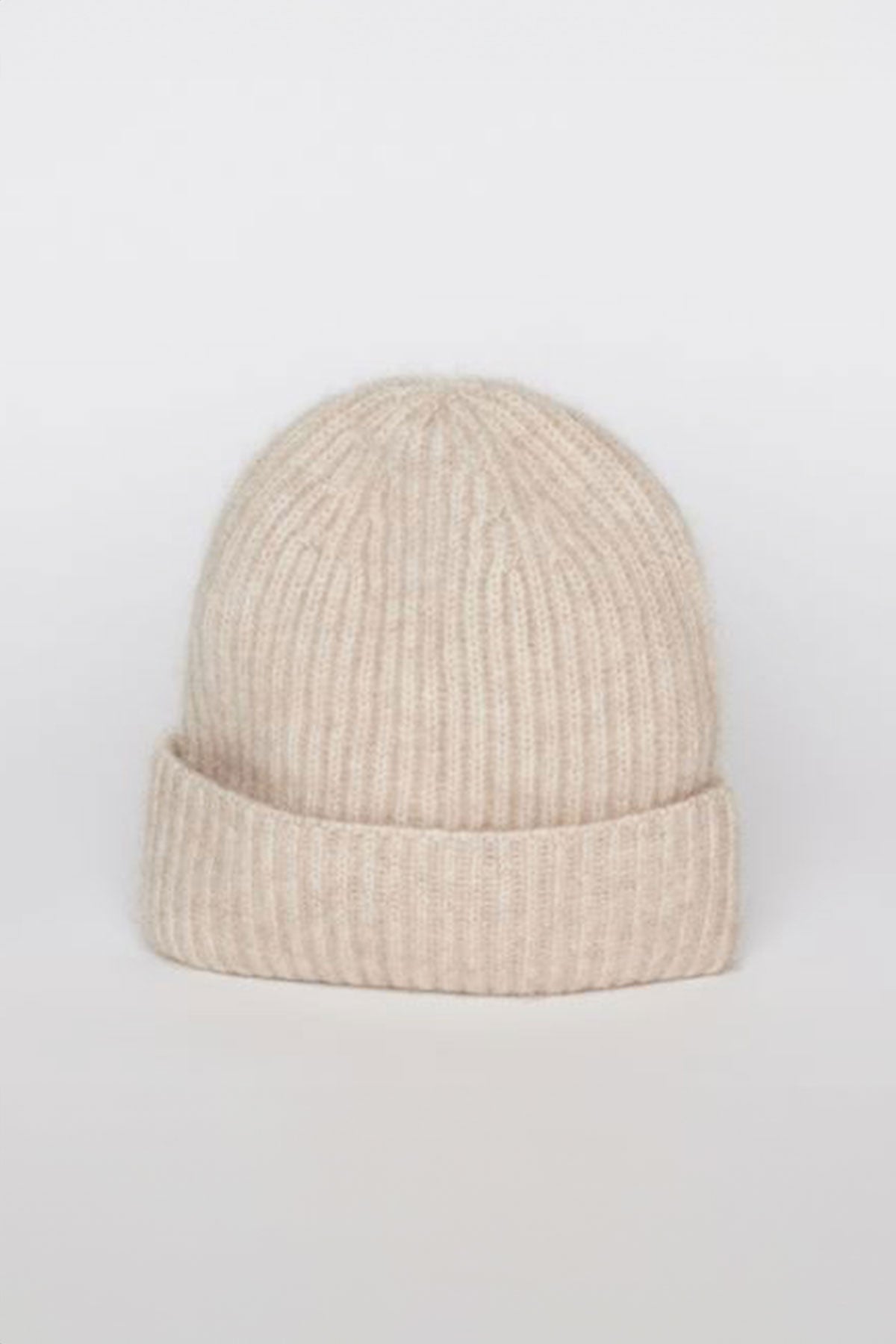   A beige CASHMERE RIB BEANIE by Velvet by Graham & Spencer, featuring a ribbed knit and folded cuff, displayed against a plain, light gray background. 