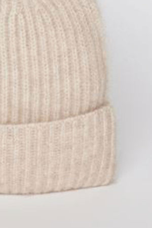 Close-up view of the CASHMERE RIB BEANIE by Velvet by Graham & Spencer, showcasing its beige knit design with ribbed texture and folded brim against a neutral background.