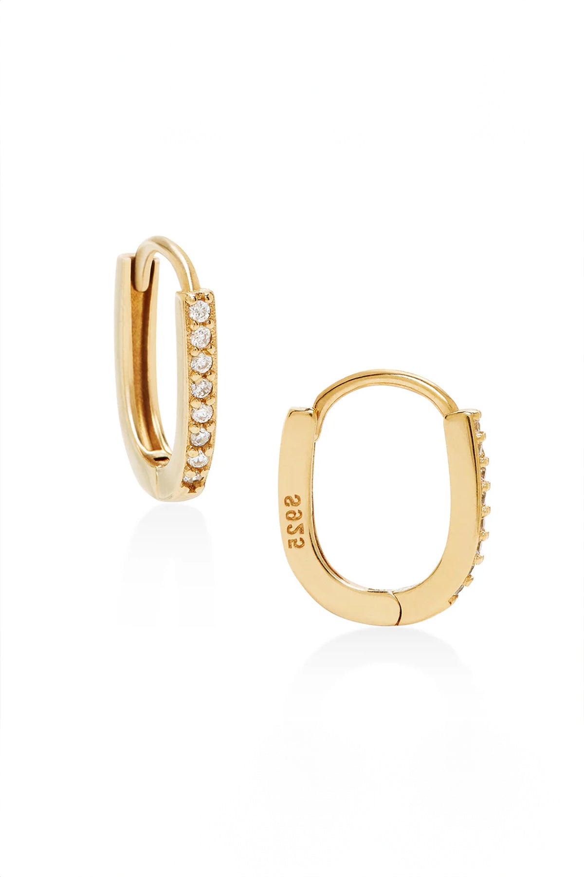   Introducing the Oblong Pave Huggies by Phyllis+Rosie—a pair of vintage gold hoop earrings, one partially open, each adorned with a row of small diamonds along the outer edge. This exquisite jewelry piece channels the timeless elegance of New York City glamour. 