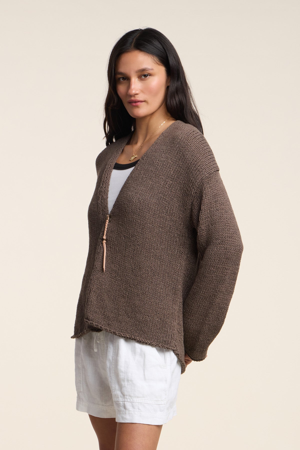 A woman wears the QUINNLY CARDIGAN by Velvet by Graham & Spencer—an open-front cotton tape yarn style—over a white top and shorts, standing against a plain light background.-41527107616961
