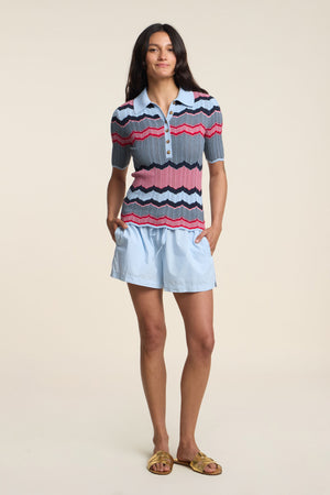 A woman stands with hands in pockets, wearing the ROBI SARONG by Velvet by Graham & Spencer against a plain background.