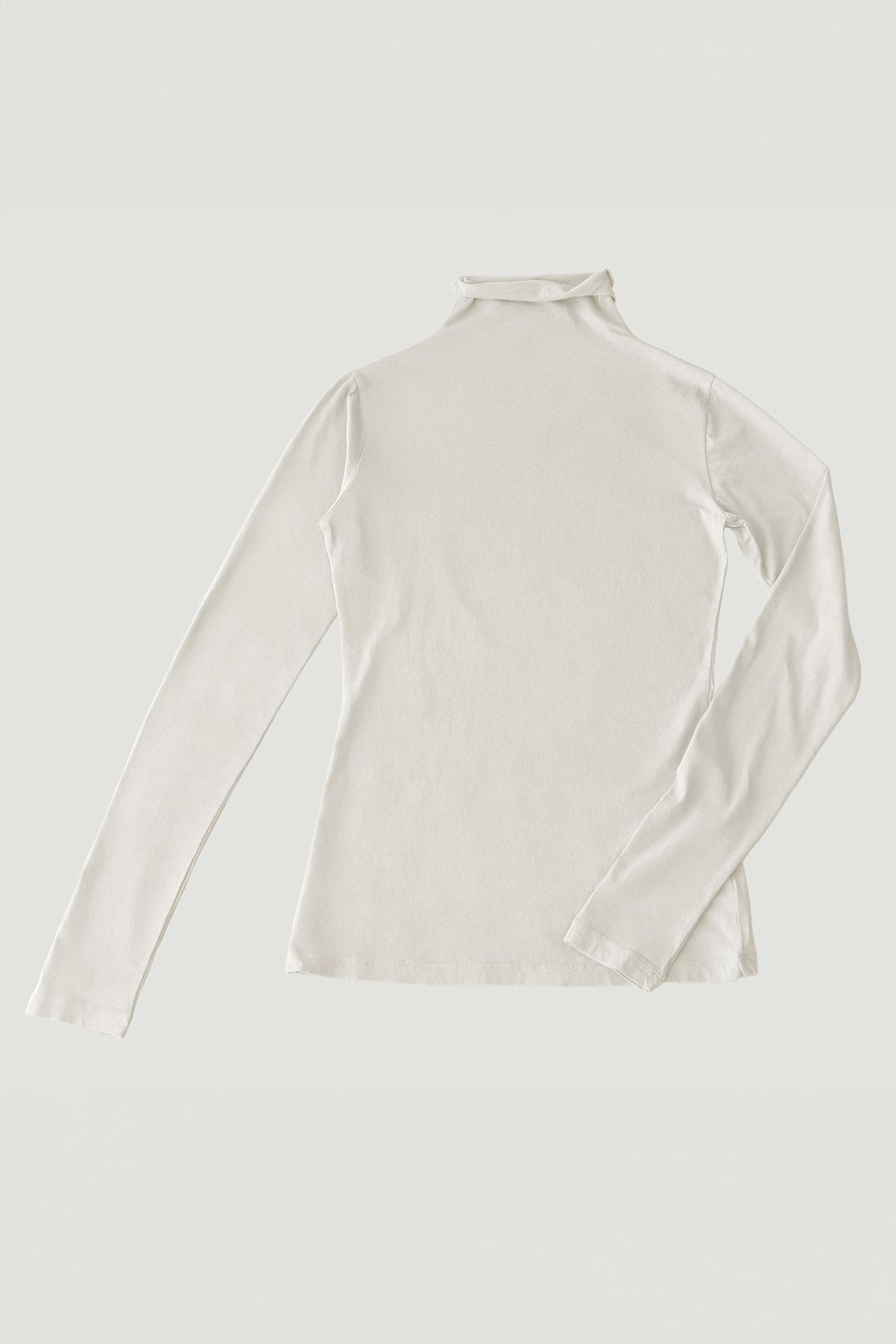   Image of the Velvet by Graham & Spencer TALISIA TEE, a long-sleeved, cream-colored turtleneck shirt laid flat on a light background, showcasing its fashion-forward appeal and the versatility it adds to any wardrobe. 