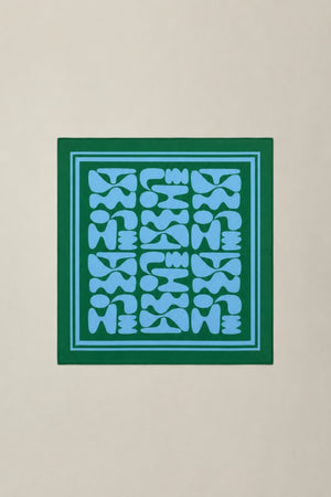 Blue geometric pattern with a green border scarf against a beige background