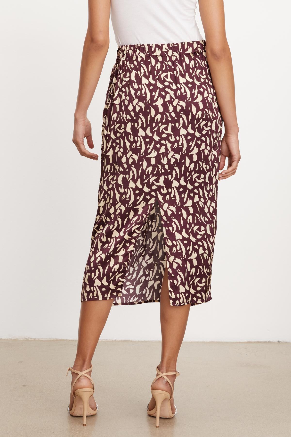   The back view of a woman wearing a Velvet by Graham & Spencer JUNO PRINTED SATIN SKIRT. 
