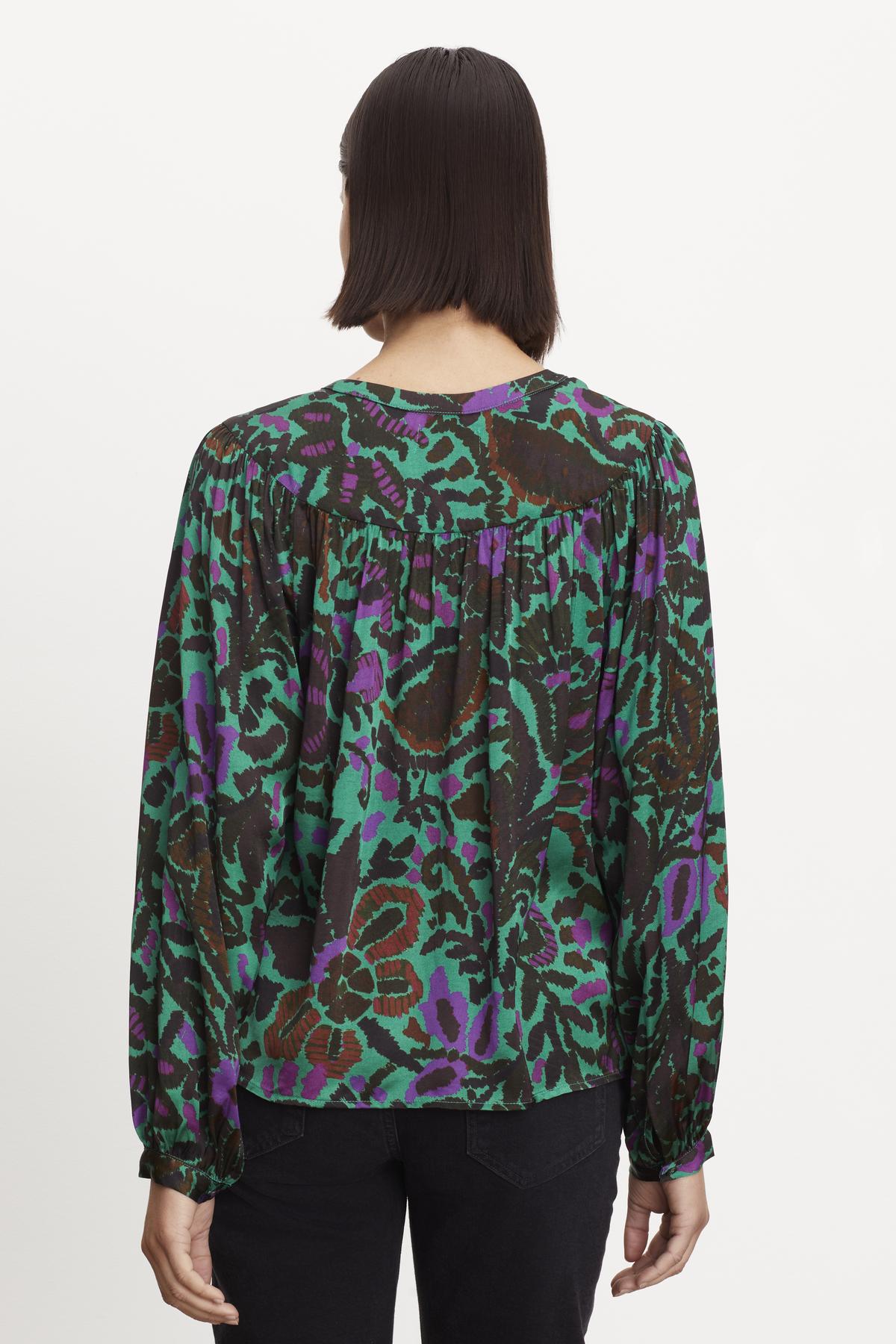   The back view of a woman wearing a REEVE PRINTED PEASANT BLOUSE by Velvet by Graham & Spencer. 