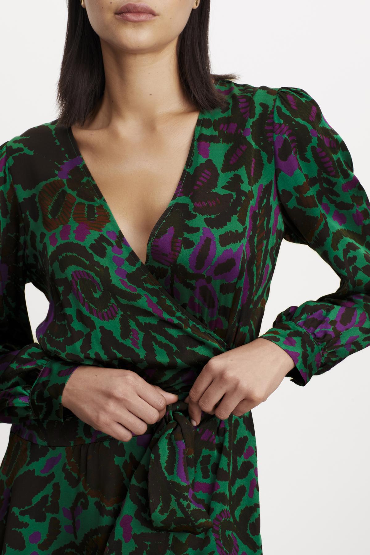   A woman wearing the Velvet by Graham & Spencer BRIDGET PRINTED SATIN WRAP DRESS with an adjustable tie waist. 