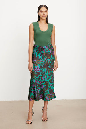 The model is wearing a green top and a KAIYA PRINTED SKIRT by Velvet by Graham & Spencer with an elastic waist for a comfortable fit.